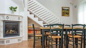 Ein Essbereich mit Kamin, Treppe und Bücherregal.