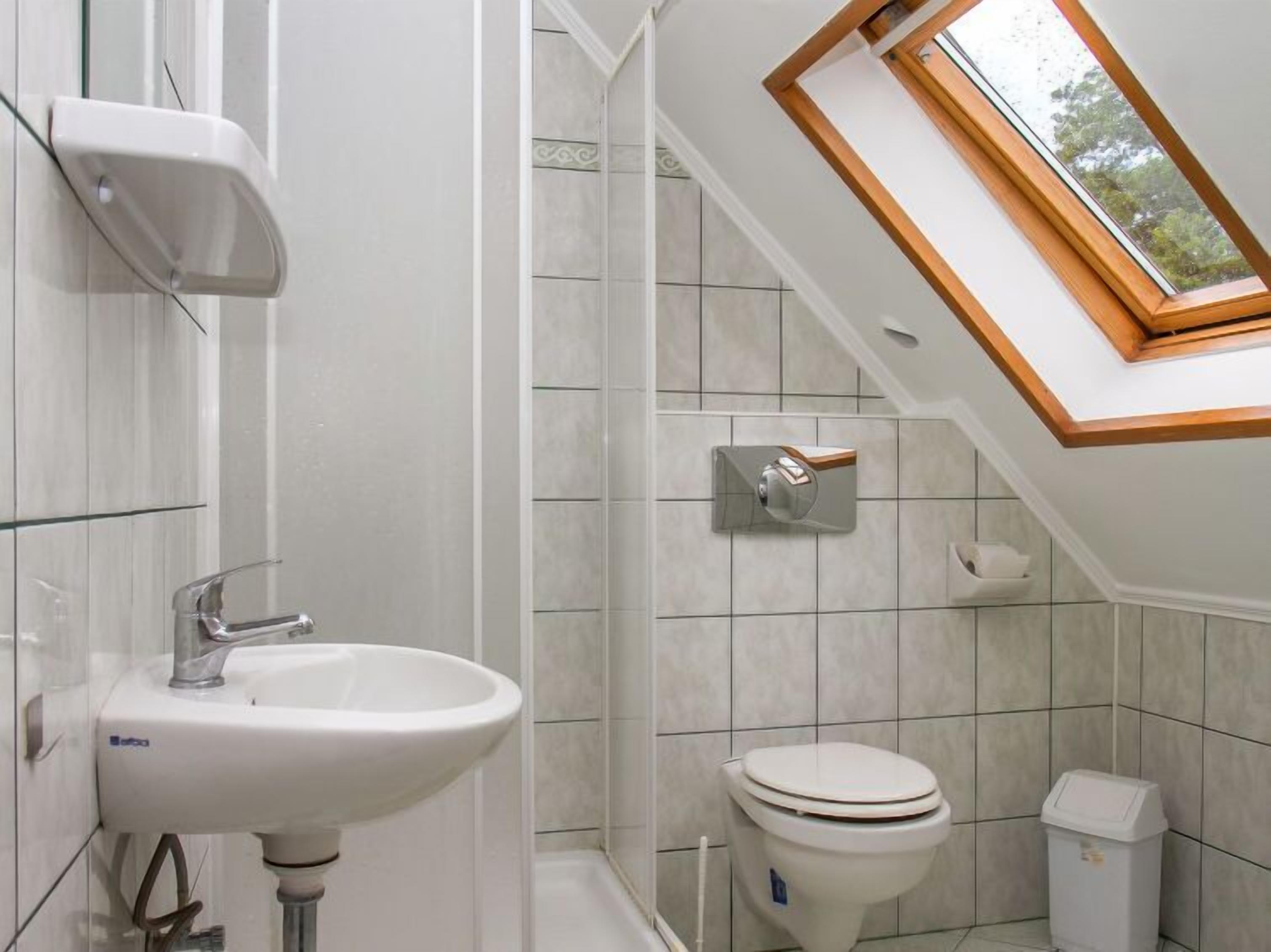 Une salle de bain avec un puits de lumière, un lavabo, des toilettes et une poubelle.