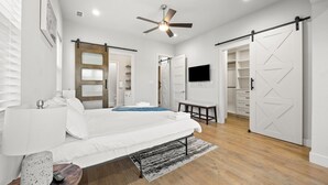 Un dormitorio con cama, ventilador de techo, televisor y armario corredera.