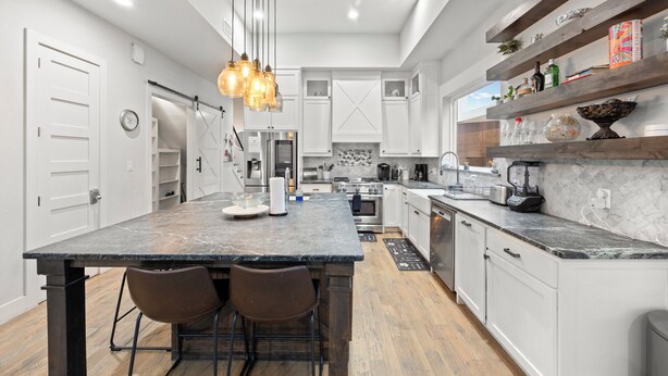 Una cocina moderna con una isla grande, armarios blancos y techo de madera.