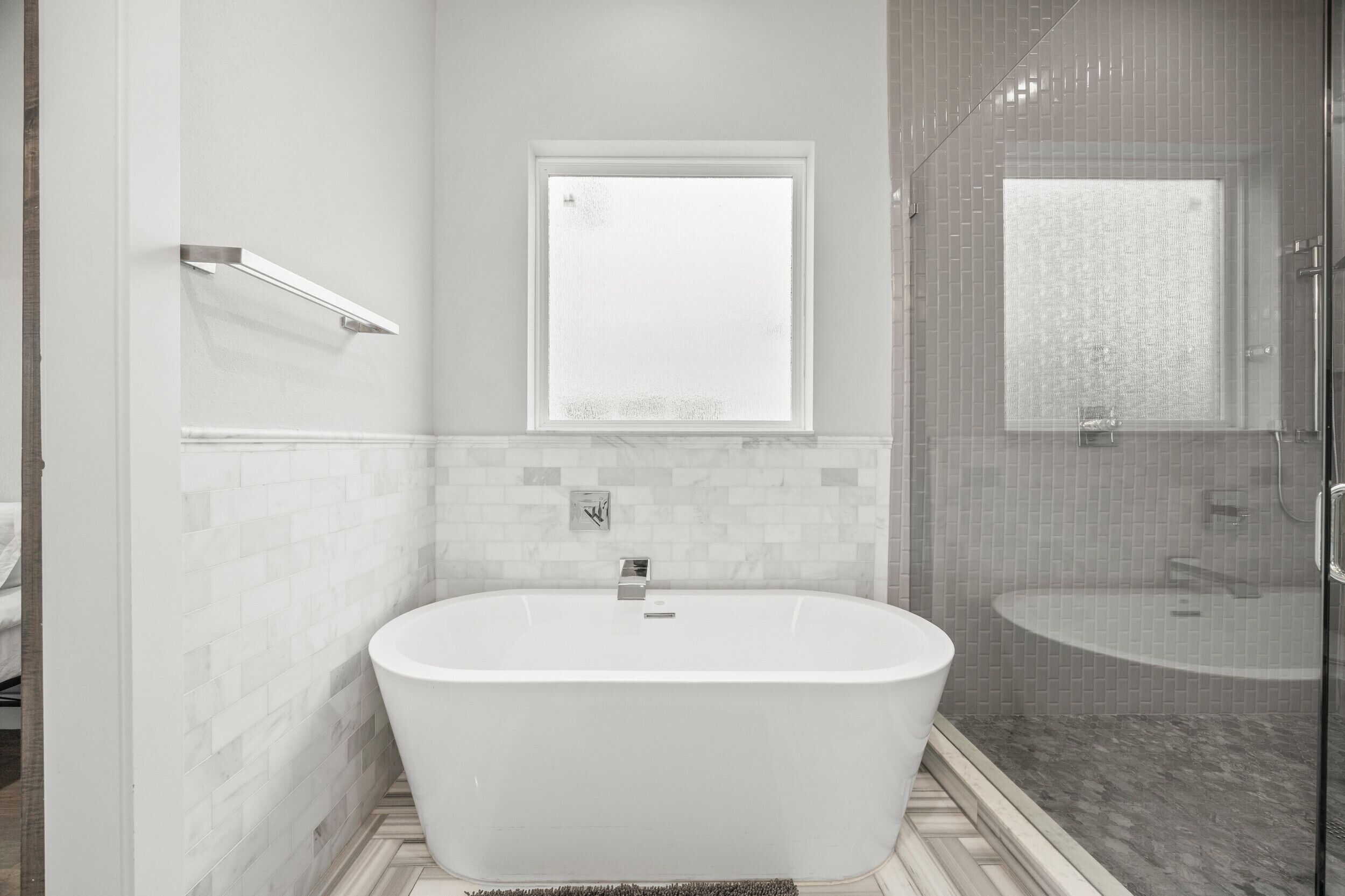 Een moderne badkamer met een vrijstaand bad, een douchecabine van glas en een spiegel bevestigd aan de muur.