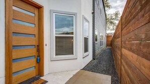 Un edificio residencial con puerta y ventana de madera, y valla también de madera.