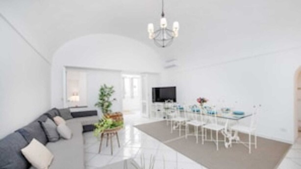 A modern living room with a sofa, dining table, chairs, a TV, and a chandelier. - Camerelle 33, Capri (Capri)