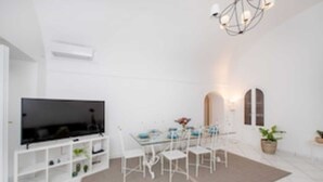 A modern living room with a flat-screen TV, white furniture, a dining table, and a chandelier. - Camerelle 33, Capri (Capri)