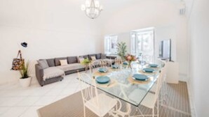 A modern living room with a glass dining table, white chairs, a gray sofa, and a chandelier. - Camerelle 33, Capri (Capri)