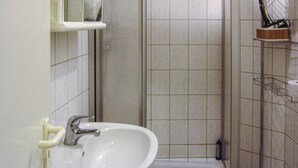 Une salle de bain avec un lavabo blanc, un miroir et un espace douche.
