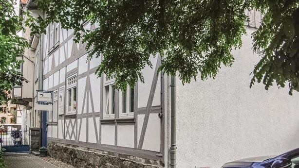 Un bâtiment traditionnel à colombages, avec une base en pierre et une façade blanche.