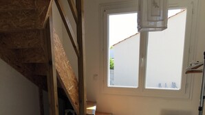 Een slaapkamer met een bed, houten trap, een raam en een radiator.