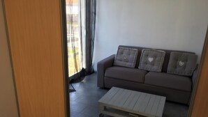 Een woonkamer met een bank, een salontafel en een schuifdeur die leidt naar een balkon.