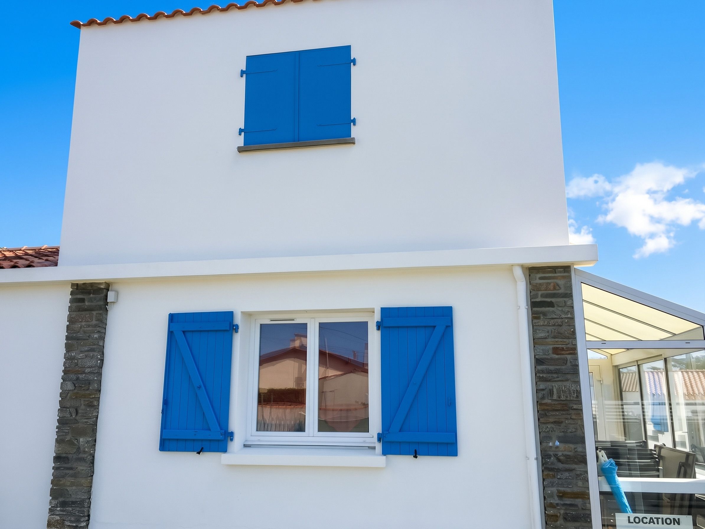 A two-story building with a white facade and blue shutters on the windows.