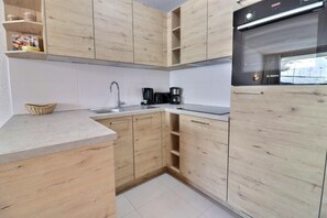 A modern kitchen with wooden cabinets, a built-in oven, and a coffee maker. - 10m from ski slopes, 4th floor, balcony, 40m², Méribel-Mottaret (Méribel - Les Allues)