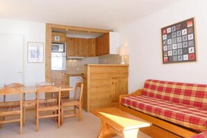 A compact living space with a wooden dining table, chairs, a sofa, and a kitchenette with a microwave and a small refrigerator. - 10m from ski slopes, 1st floor, balcony, 40m², Méribel-Mottaret (Méribel - Les Allues)