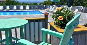 Ein Poolbereich mit Holzterrasse, einem runden Tisch und einem Blumenbeet.