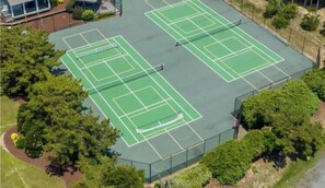 En udendørs tennisbane omgivet af træer.
