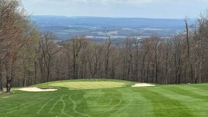 A golf course with a clear view of the surrounding landscape, including trees and distant hills. - True Ski-In/Ski-Out on Comet & Voyager, Sleeps 9, Fireplace, Pet Friendly (Hidden Valley)