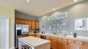 Una cucina moderna con mobili in legno, un frigorifero in acciaio inossidabile e una grande isola.
