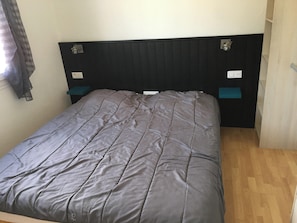 A bed with a dark headboard, two bedside tables, and a light switch on the wall.