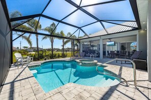 A swimming pool with a glass ceiling, surrounded by lounge chairs and a patio area. - Fall Special, Beautiful Pelican Gulf Access Waterfront Home With Private Pool (Cape Coral)