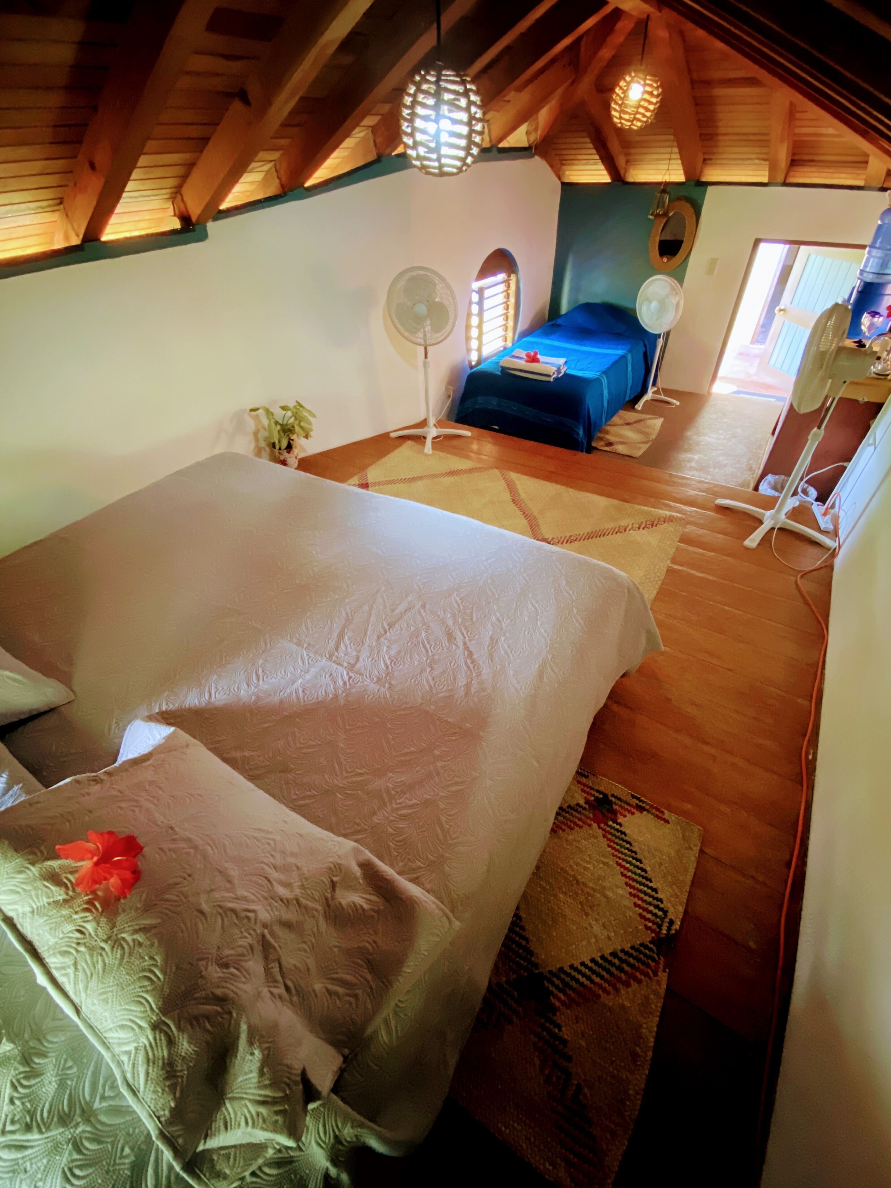 Una habitación acogedora con dos camas, un ventilador y un dispensador de agua.