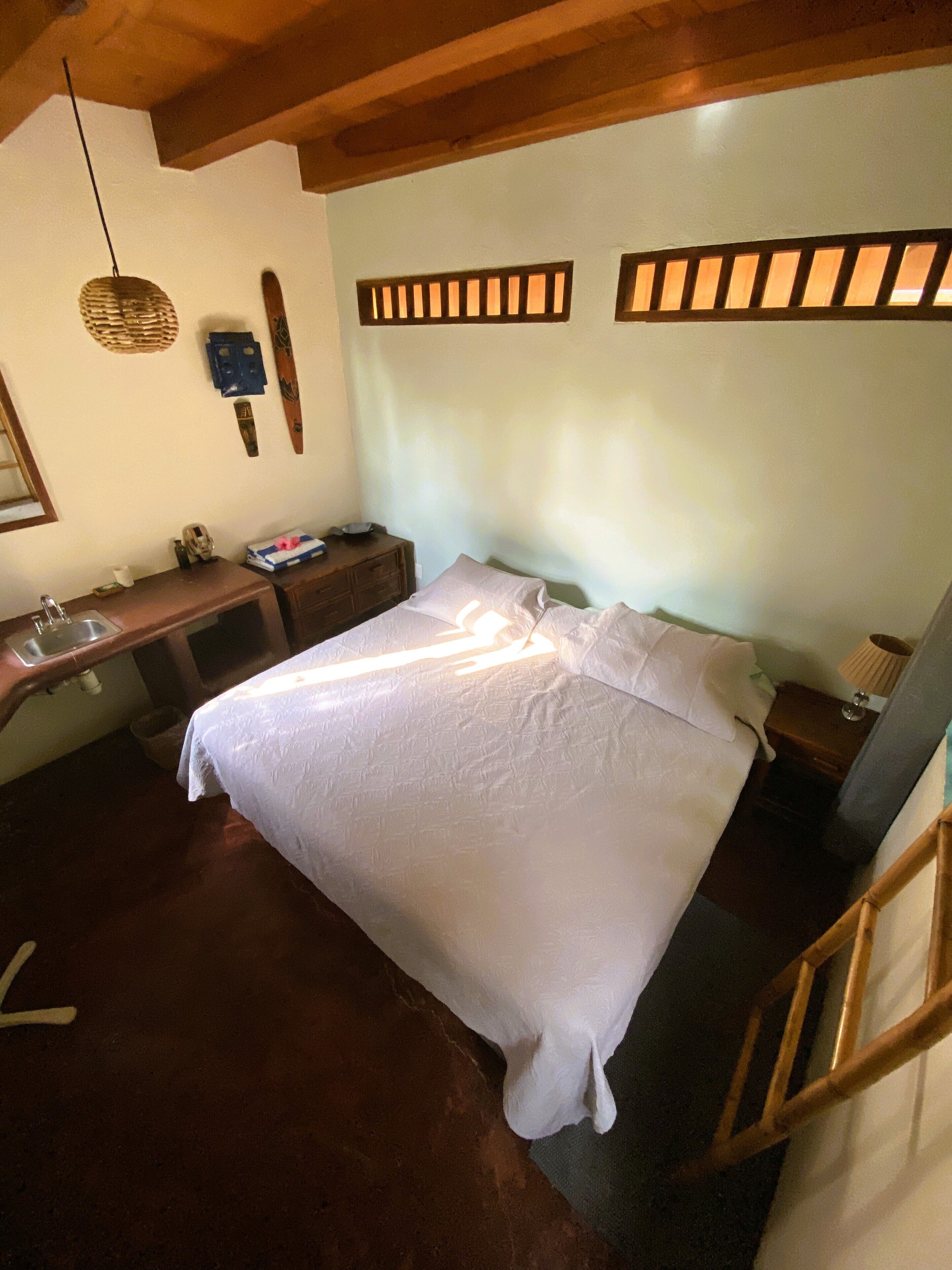 A bedroom with a bed, a desk, and a nightstand.