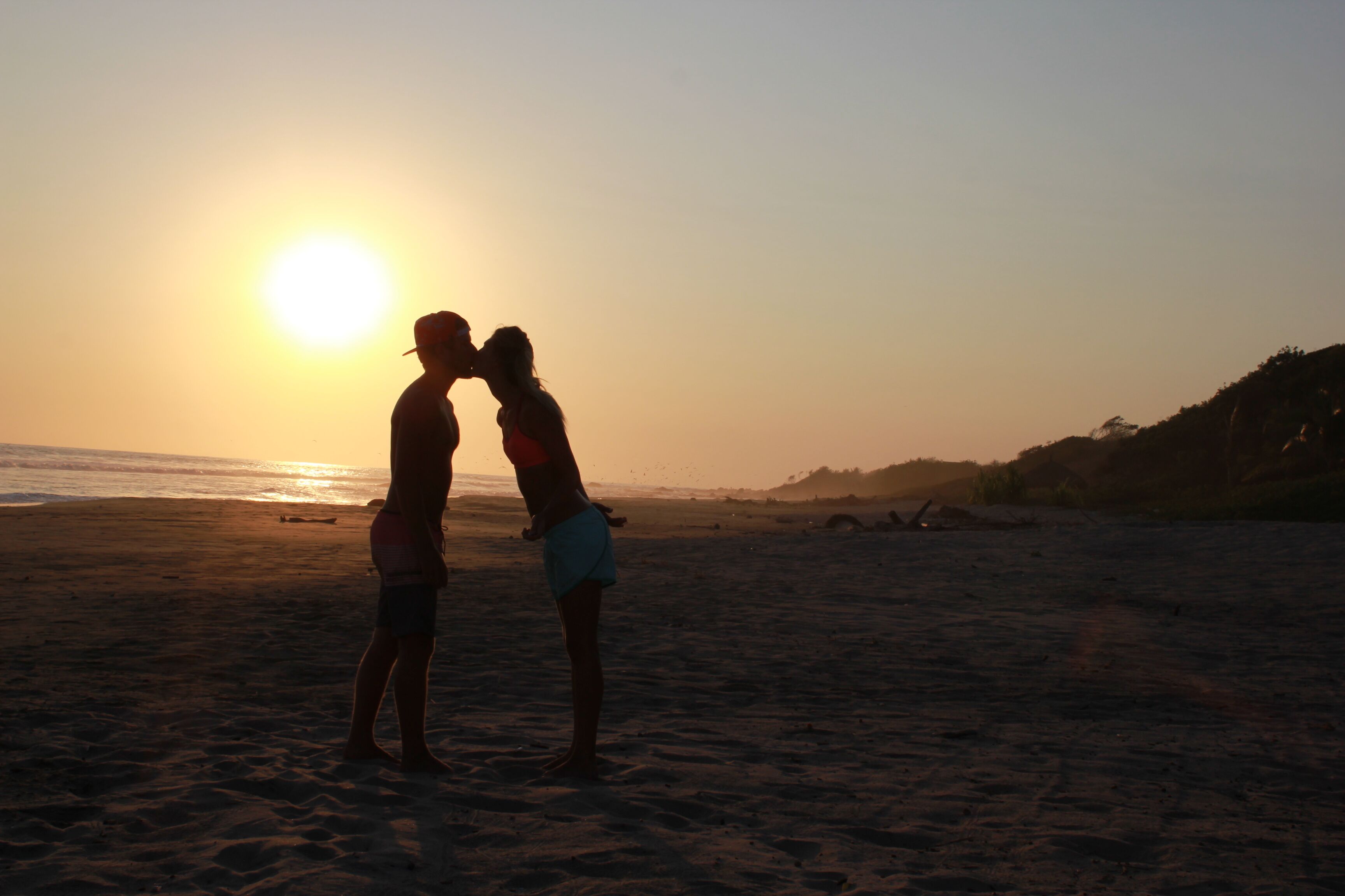 Una pareja de pie en la playa al atardecer.