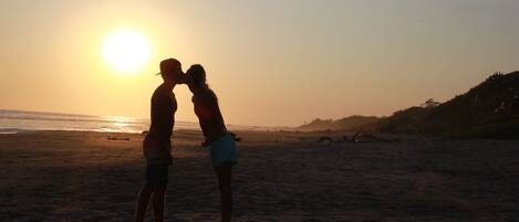 Una pareja de pie en la playa al atardecer.