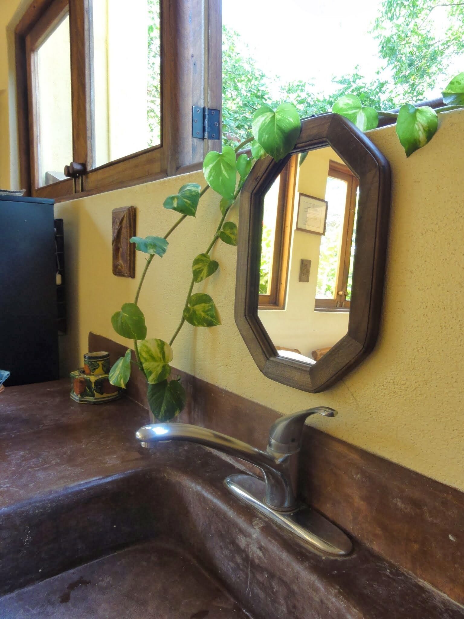 A bathroom with a wooden vanity, a sink with a modern faucet, and a mirror with a heart-shaped frame.