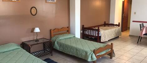 Una habitación con dos camas individuales, una mesita de noche con una lámpara y una silla.