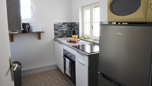 A compact kitchen with a microwave, refrigerator, and a small window. - Le Verdier (Dieppe)