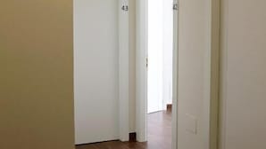 Un pasillo con suelo de madera y paredes blancas, con puertas numeradas 43 y 42.