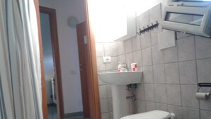 A bathroom with a toilet, sink, and shower area.