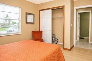 A bedroom with a bed, a chair, a fan, and a closet. - Centrally located 3Br2Ba Pool Home available for LONGER STAYS, Monthly Discounts (Port St. Lucie)