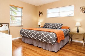A bedroom with a bed, two bedside lamps, a window with blinds, and a painting on the wall. - Centrally located 3Br2Ba Pool Home available for LONGER STAYS, Monthly Discounts (Port St. Lucie)