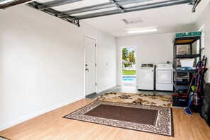 A laundry room with a washing machine, dryer, and shelves with cleaning supplies.