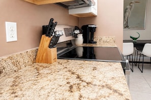 Cozinha com bancadas de granito, cafeteira e porta-facas.