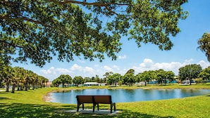 Un parque con un banco, un estanque y árboles.