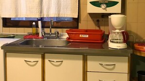 Et køkken med vask, kaffemaskine og opvaskestativ.