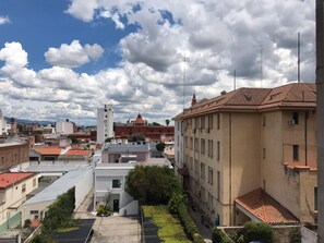 Un paisaje urbano con una iglesia destacada, una mezcla de edificios residenciales y comerciales, y un cielo despejado.