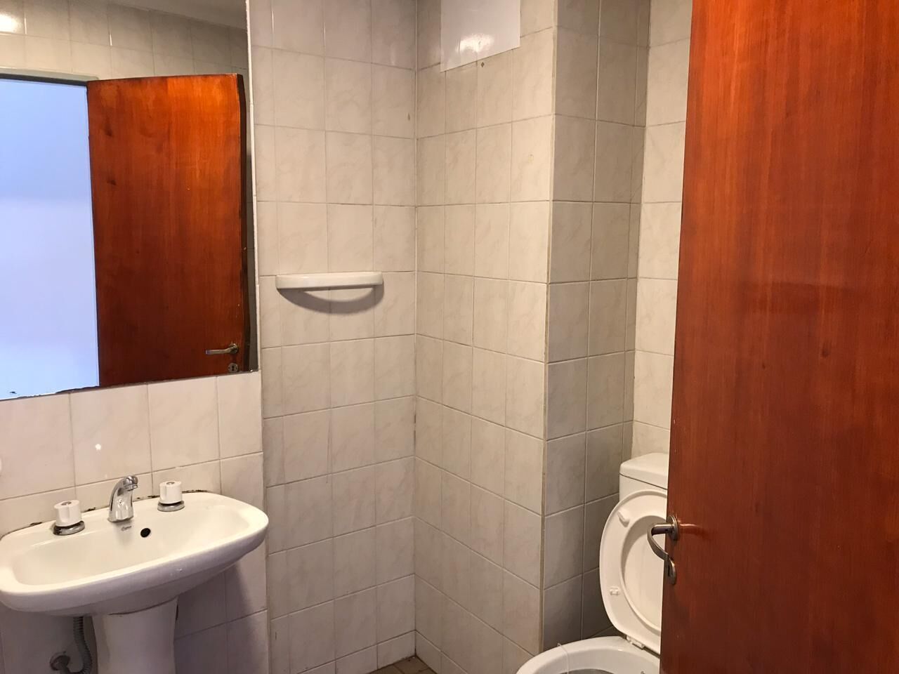A bathroom with a white sink, a mirror, and a toilet.