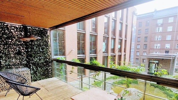 A balcony with a wooden floor, a table, a chair, and a potted plant. - Superb sijainti + hiljaisuus + sauna (Helsinki)