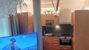 A modern kitchen with wooden cabinets, a built-in microwave, and a stainless steel oven. - Superb sijainti + hiljaisuus + sauna (Helsinki)