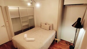 A bedroom with a bed, a wardrobe, a ceiling light, and a floor lamp. - Superb sijainti + hiljaisuus + sauna (Helsinki)