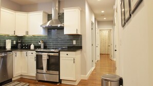 Una cocina moderna con armarios blancos, electrodomésticos de acero inoxidable y piso de madera.