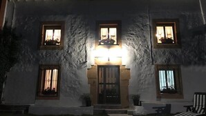 Un bâtiment doté d’une entrée centrale, de nombreuses fenêtres et d’un chemin menant à un fauteuil.