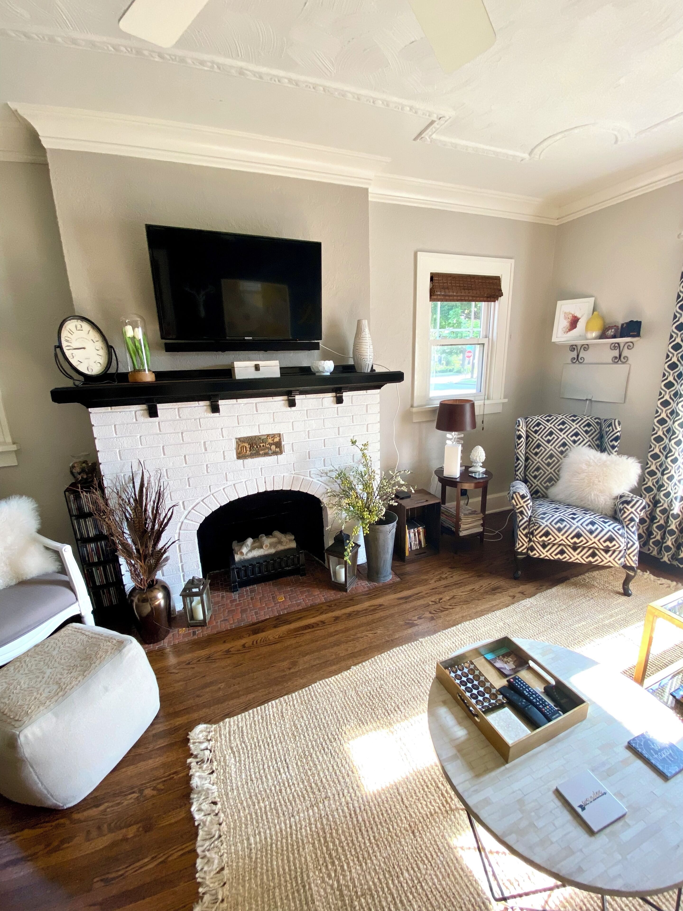 A living room with a fireplace, a television mounted above it, and a patterned armchair.