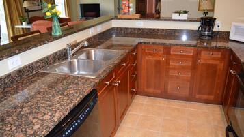 A kitchen with granite countertops, wooden cabinets, a dishwasher, and a coffee maker.