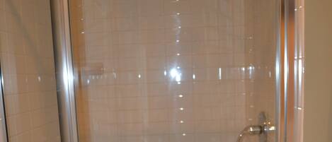 A glass-enclosed shower with a tiled floor and a visible drain.