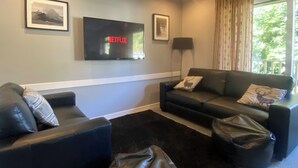 A living room with a flat-screen TV mounted on the wall, a sofa, a coffee table, and a rug. - 3 bedroom accommodation in Oban (Oban)