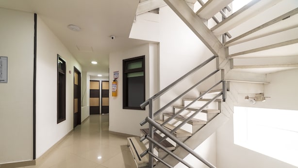A modern hotel corridor with a metal staircase, a fire extinguisher, and a ceiling-mounted smoke detector. - Expo Hotel Ferial (Bogotá)