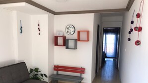 A living room with a sofa, a bench, a clock, and a plant. - Departamento Belgrano 6 (Salta)